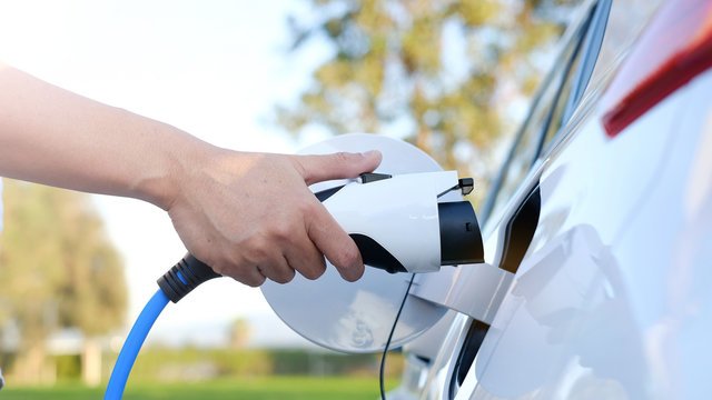 Electric car being plugged in to a home charging connector
